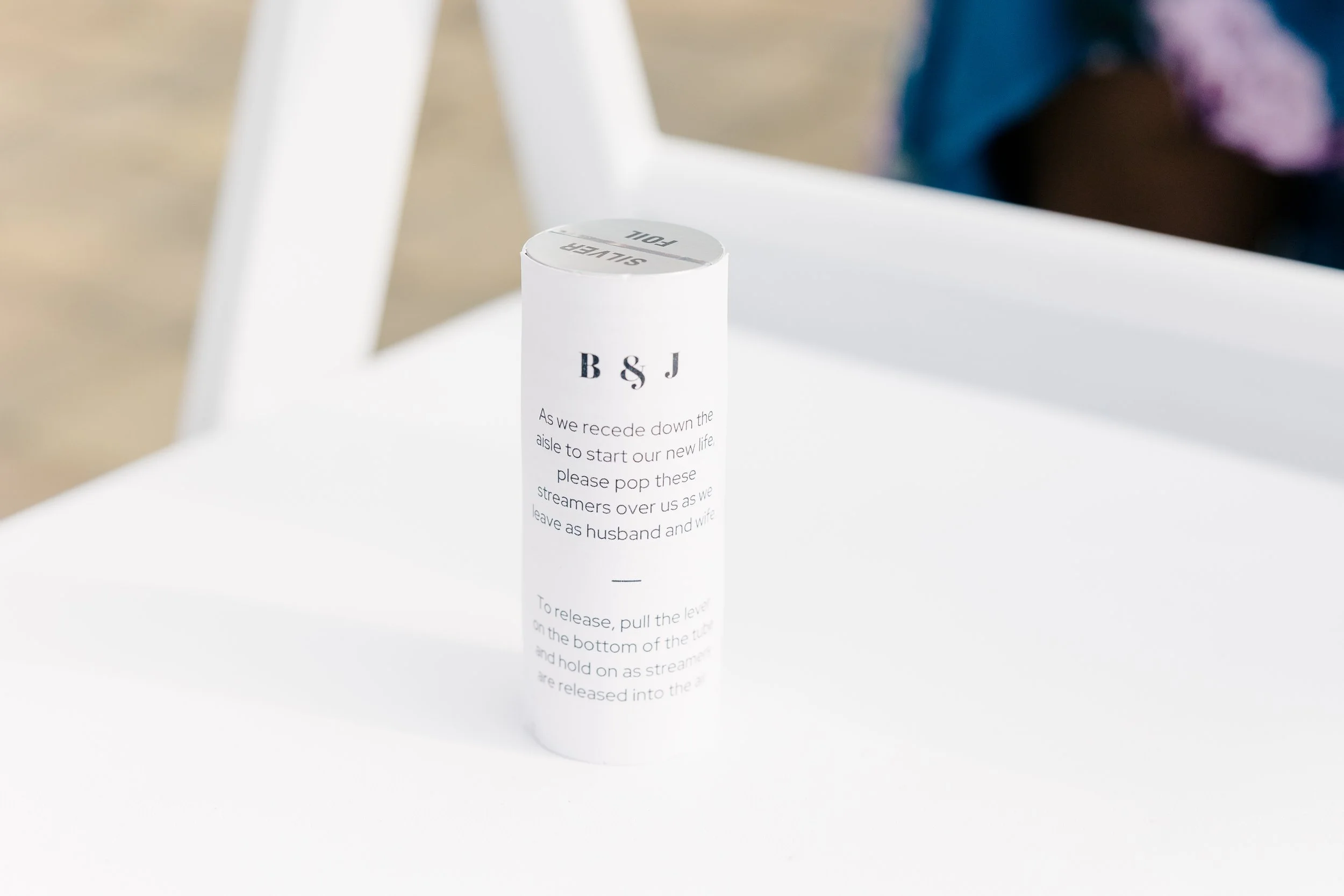 A confetti popper with a custom label sitting on a white chair.