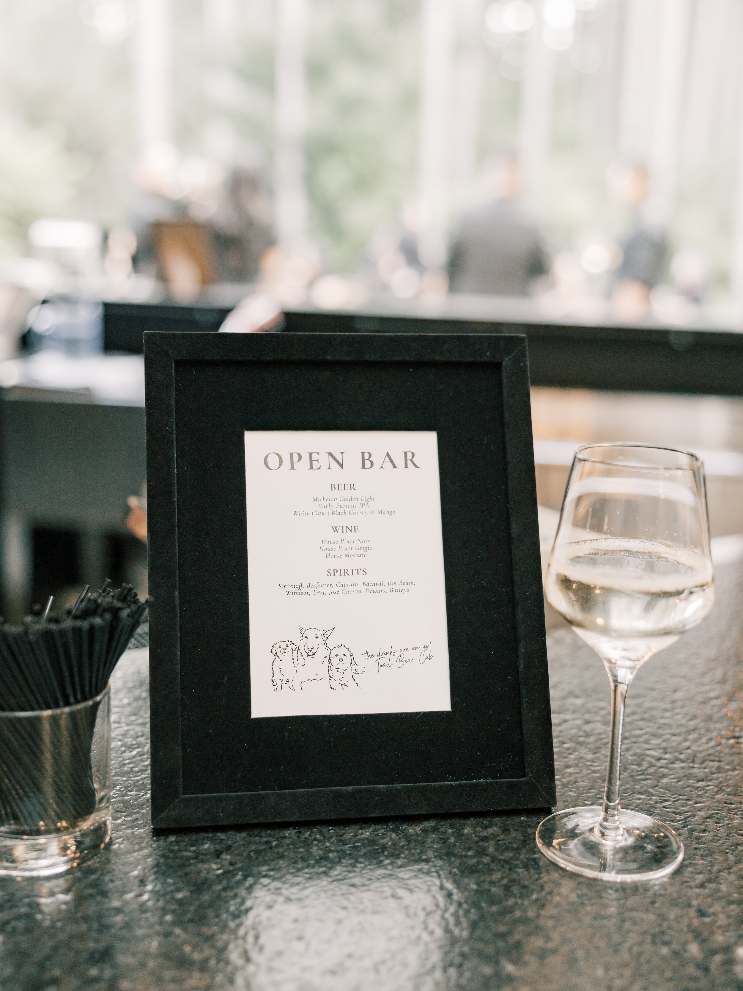 Black velvet bar menu frame with a sketch of dogs and a wine glass next to it