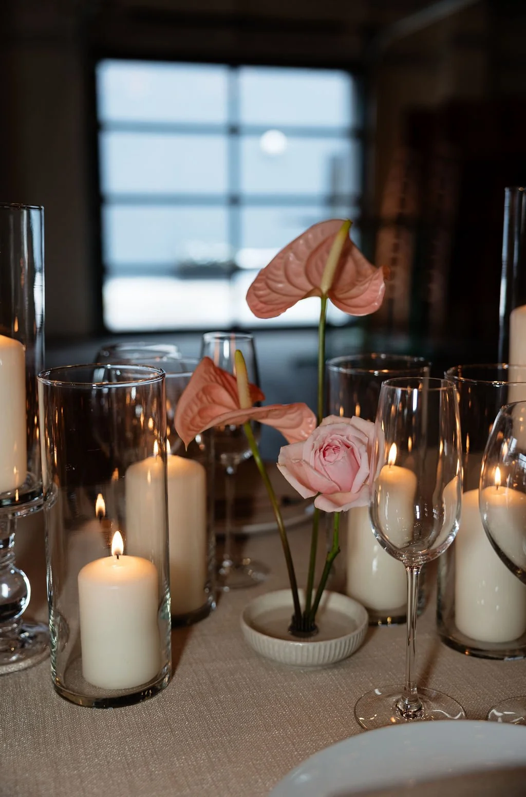 A close up of pink flowers on a wedding reception table with lit candles surrounding it.