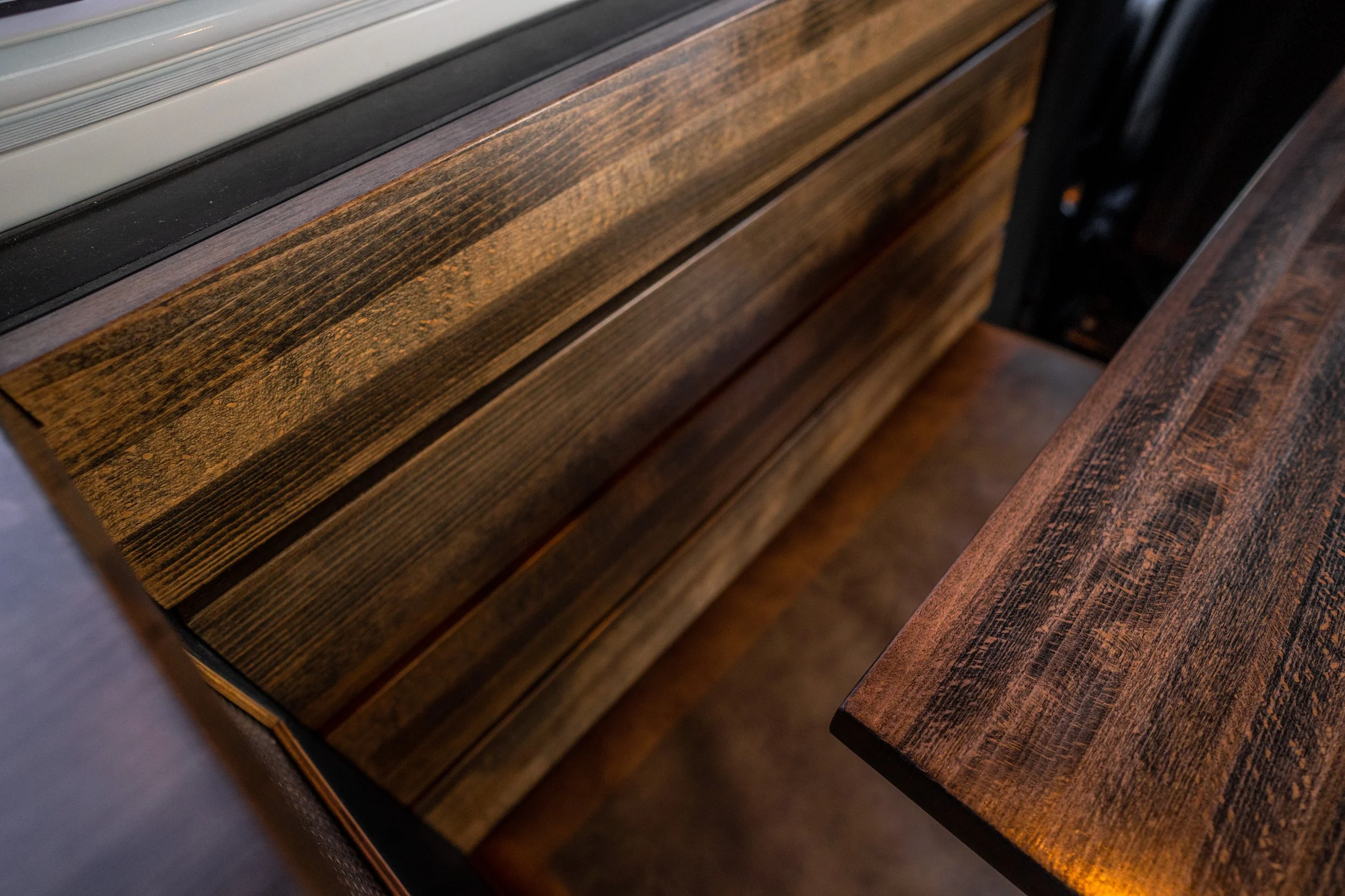 Close-up of dark and light brown wooden furniture with visible wood grain, including a drawer and a table edge.