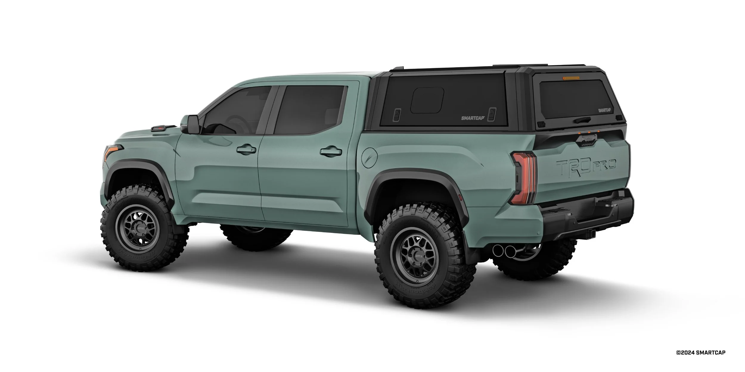 A rugged green pickup truck with large off-road tires, black fender flares, a black camper shell, and the word 'TRD PRO' embossed on the tailgate.