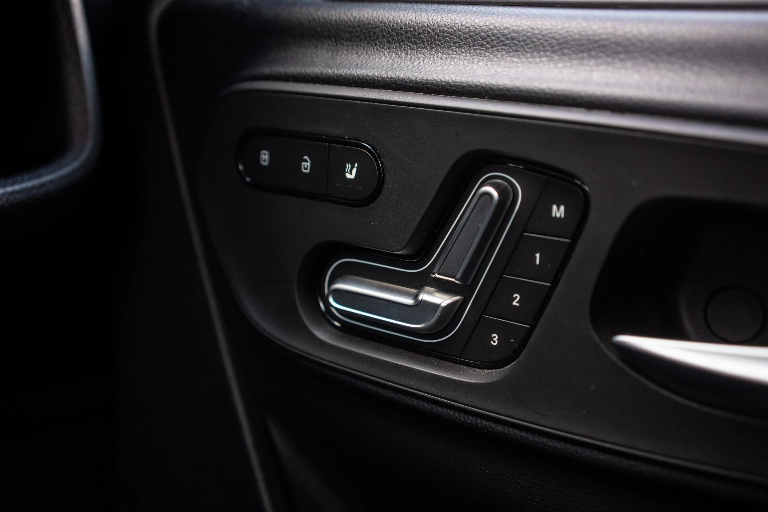 A car seat adjustment panel with buttons for seat memory settings, seat position controls, and seat heating.