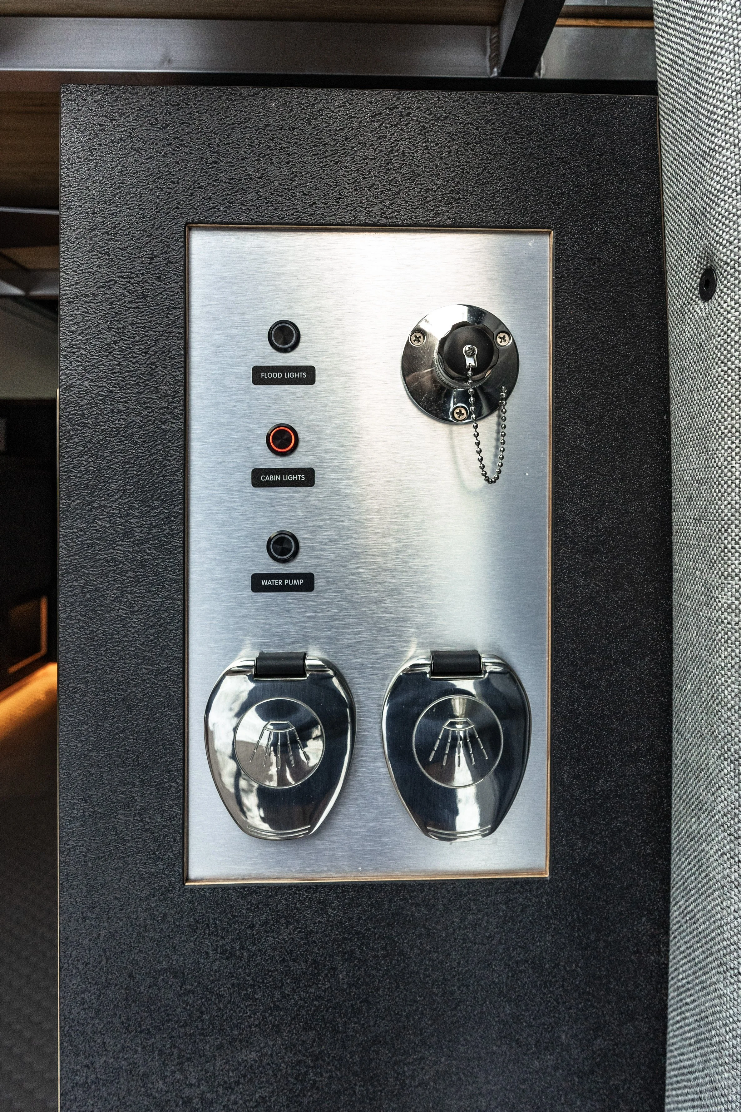 Control panel with switches for flood lights, cabin lights, and water pump, along with a key lock and two secured power outlets.
