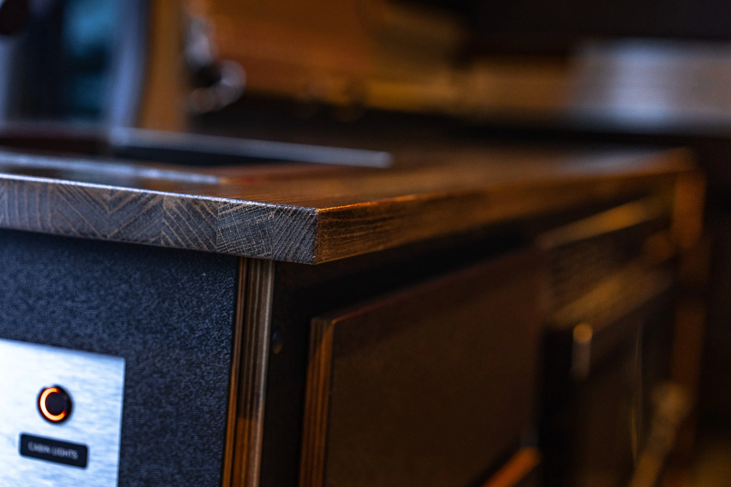 Close-up of a wooden cabinet or furniture with a dark finish and detailed grain pattern, topped with a wooden surface.