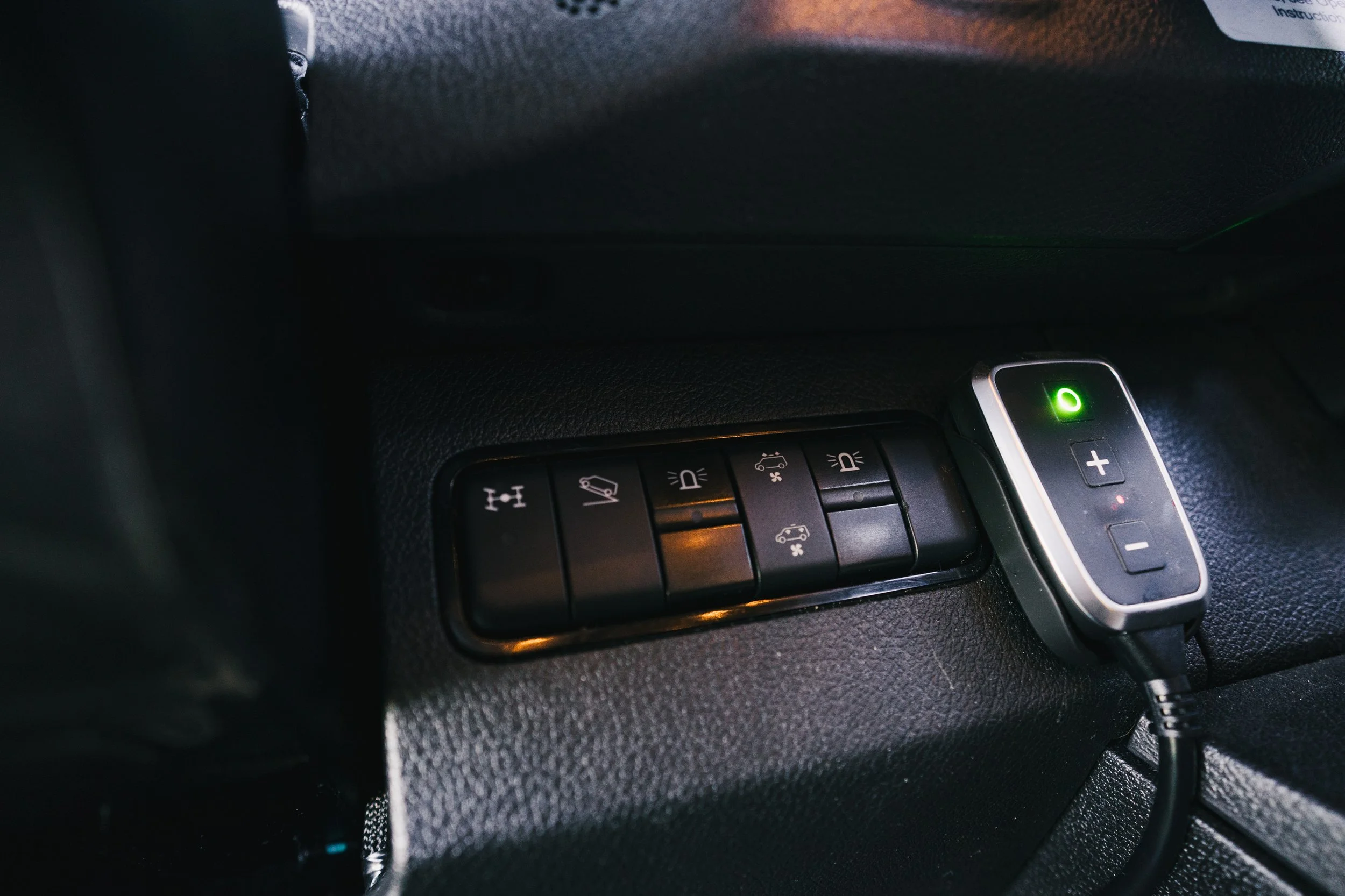 Car dashboard with control panel and a small device plugged into a port.