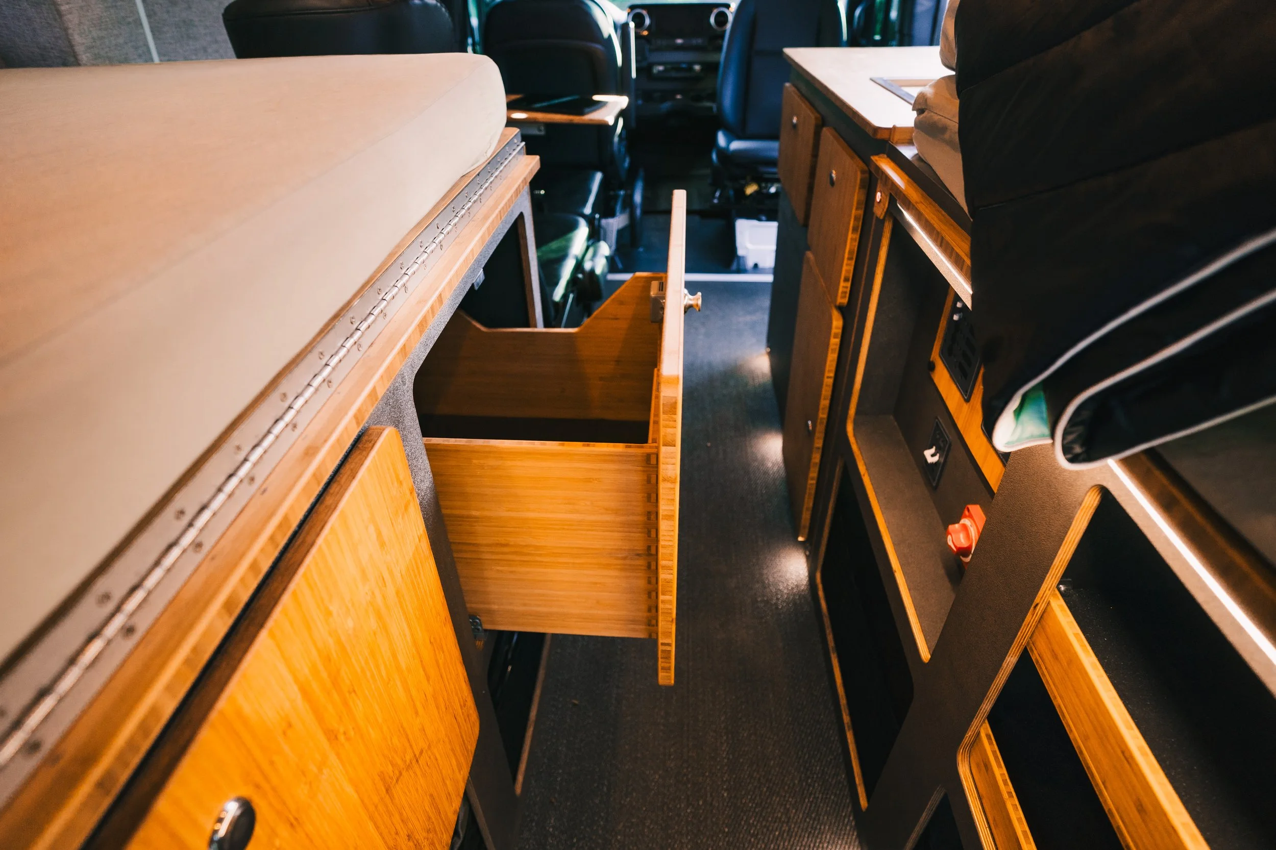 Interior of a vehicle with open drawers and wooden cabinetry along the sides.
