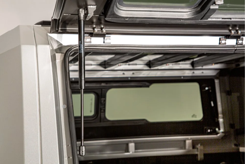 Close-up view of the inside of a 3D printer, showing metal components, a stepper motor, and a partially open cover.