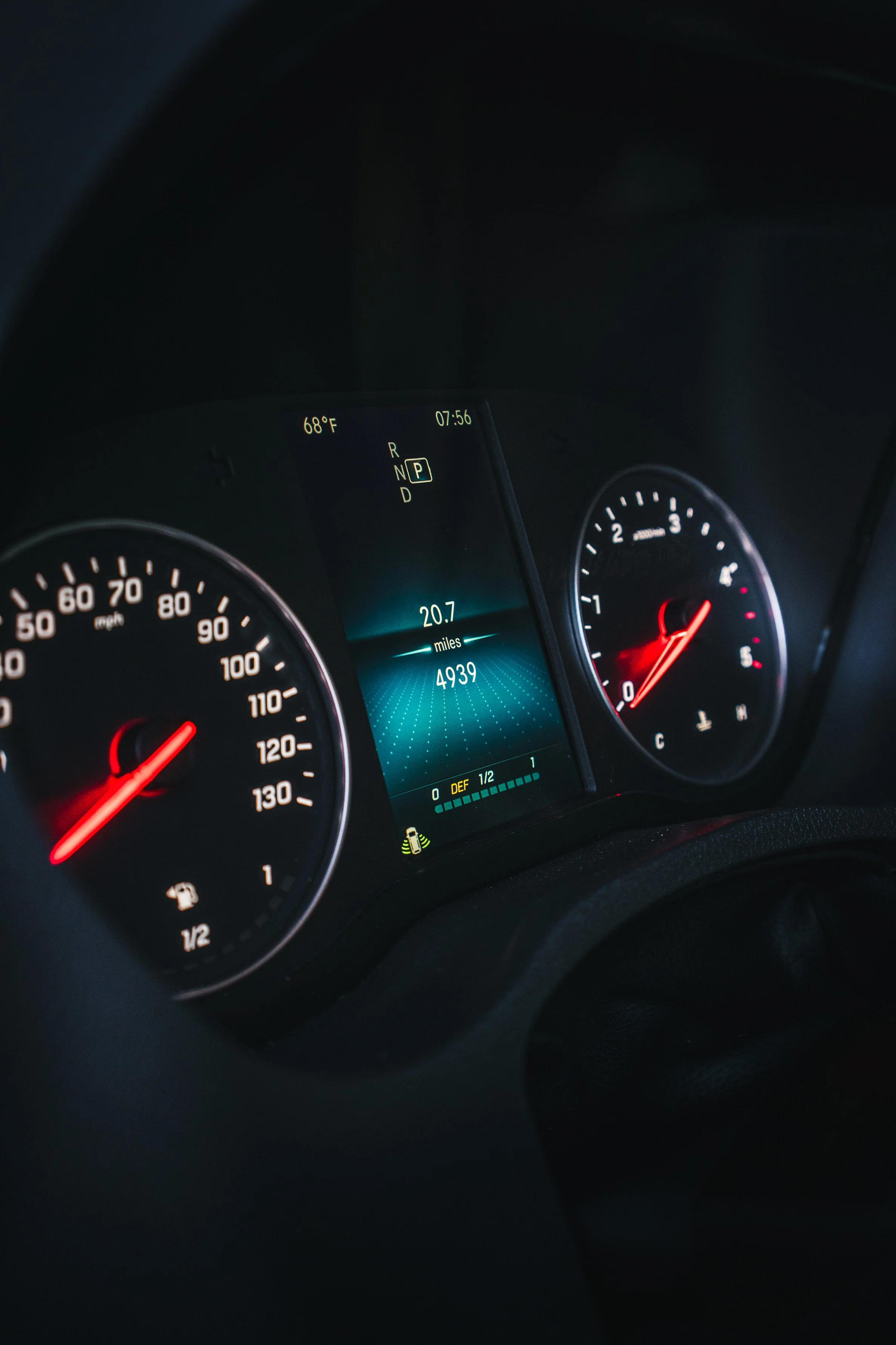 Close-up of a car dashboard showing the speedometer, tachometer, and a central digital display with mileage, fuel level, and gear indicator.