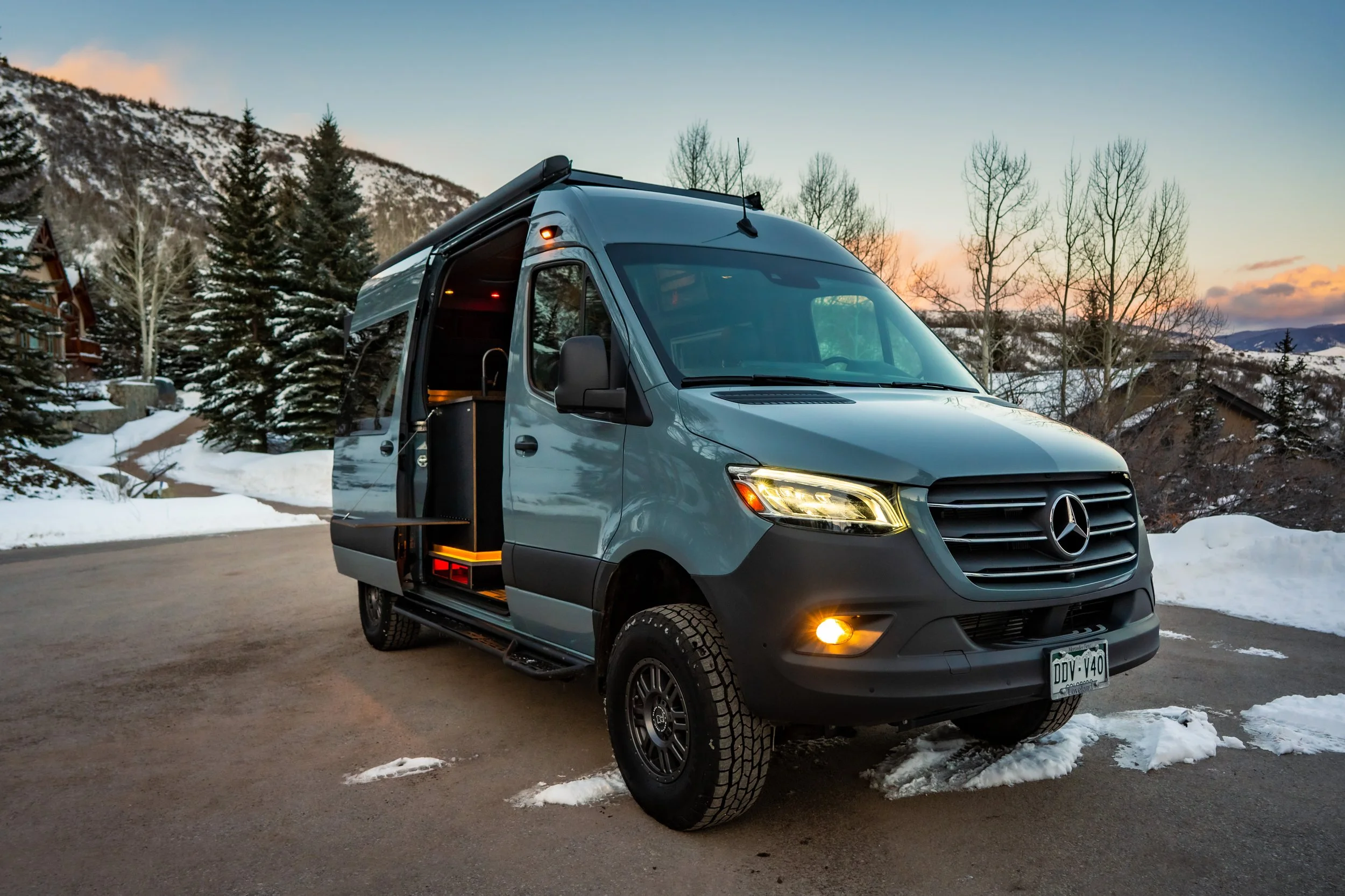 A blue Sprinter Van with its door open showing a beautiful interior designed and built by White River Overland in Aspen, CO
