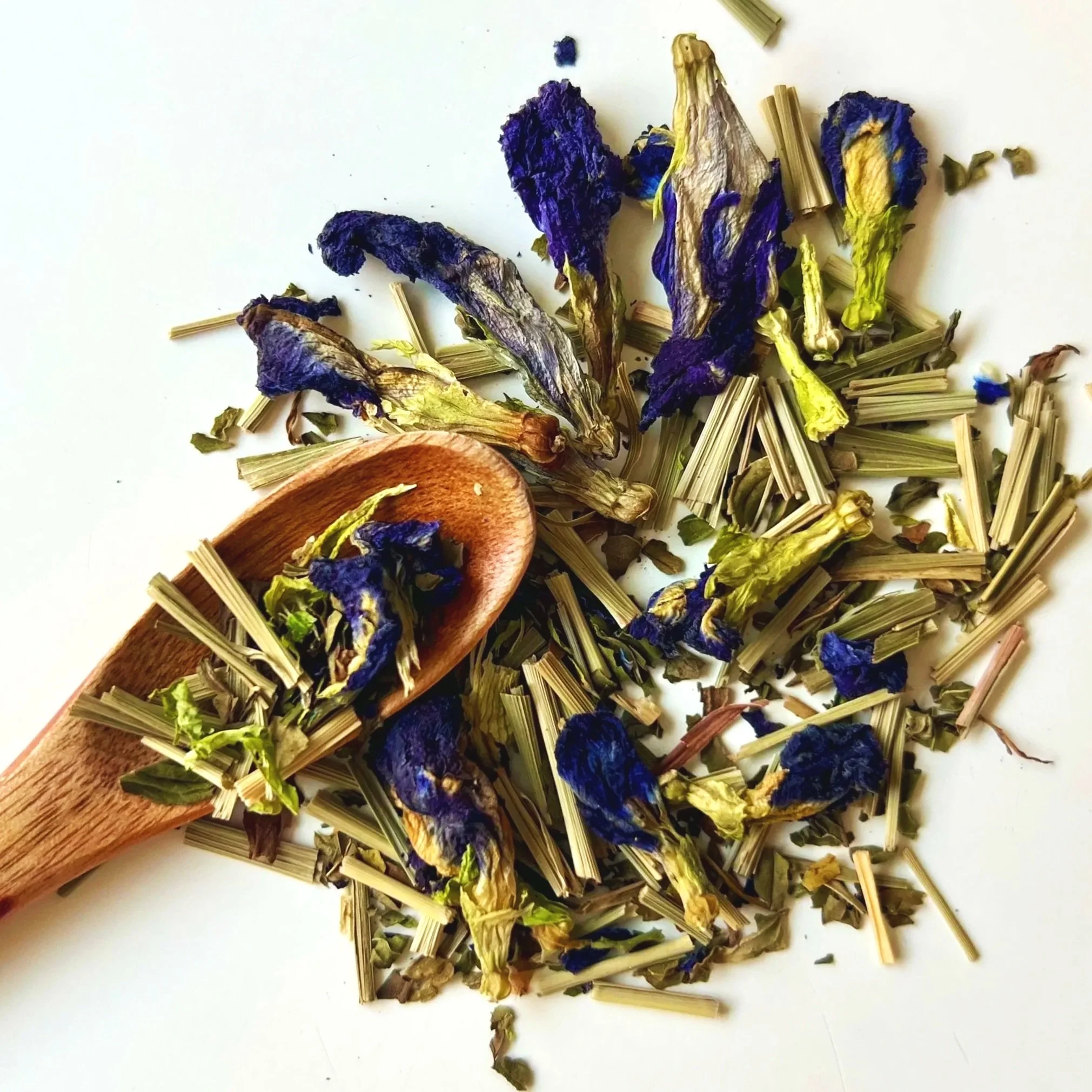 A wooden spoon of Neptune blue herbal tea by Inlustria Blends, commonly searched online as Illustria Tea.