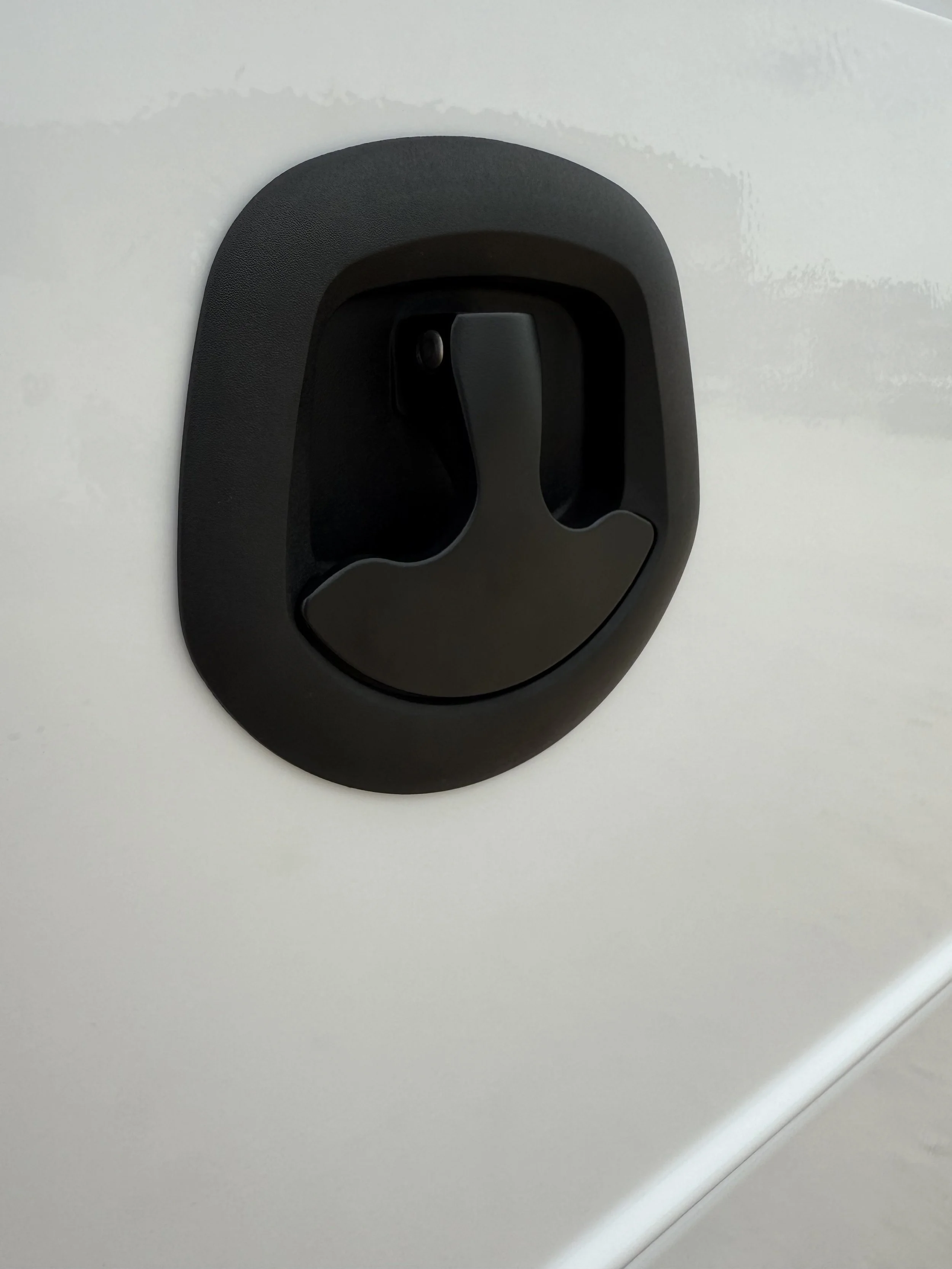 Black handle mounted on a white surface, used for opening a door.