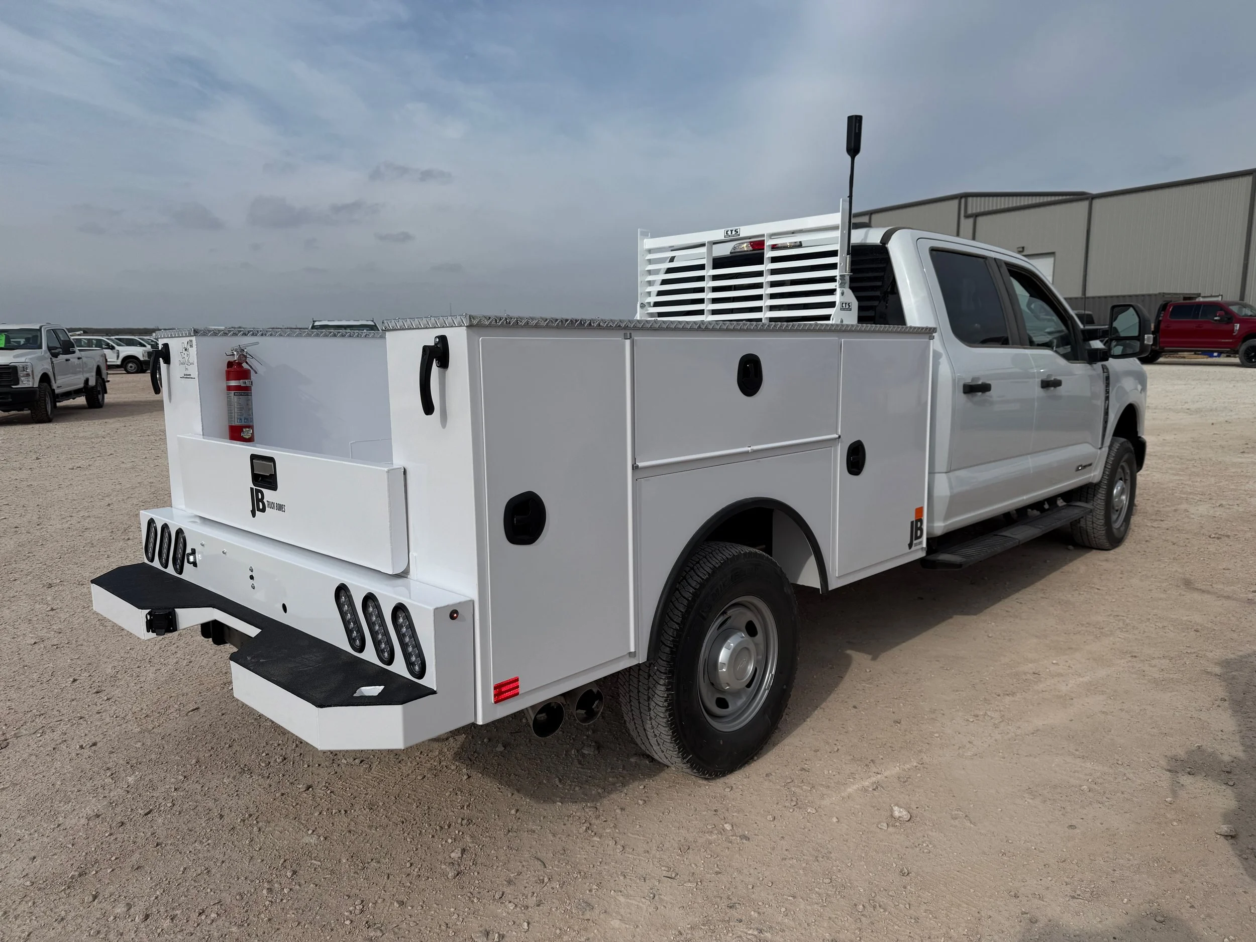 White utility truck with storage compartments, fire extinguisher, and LED lights in a dirt lot