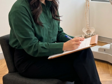 Experienced female chiropractor, Joy, taking notes during a patient consultation.