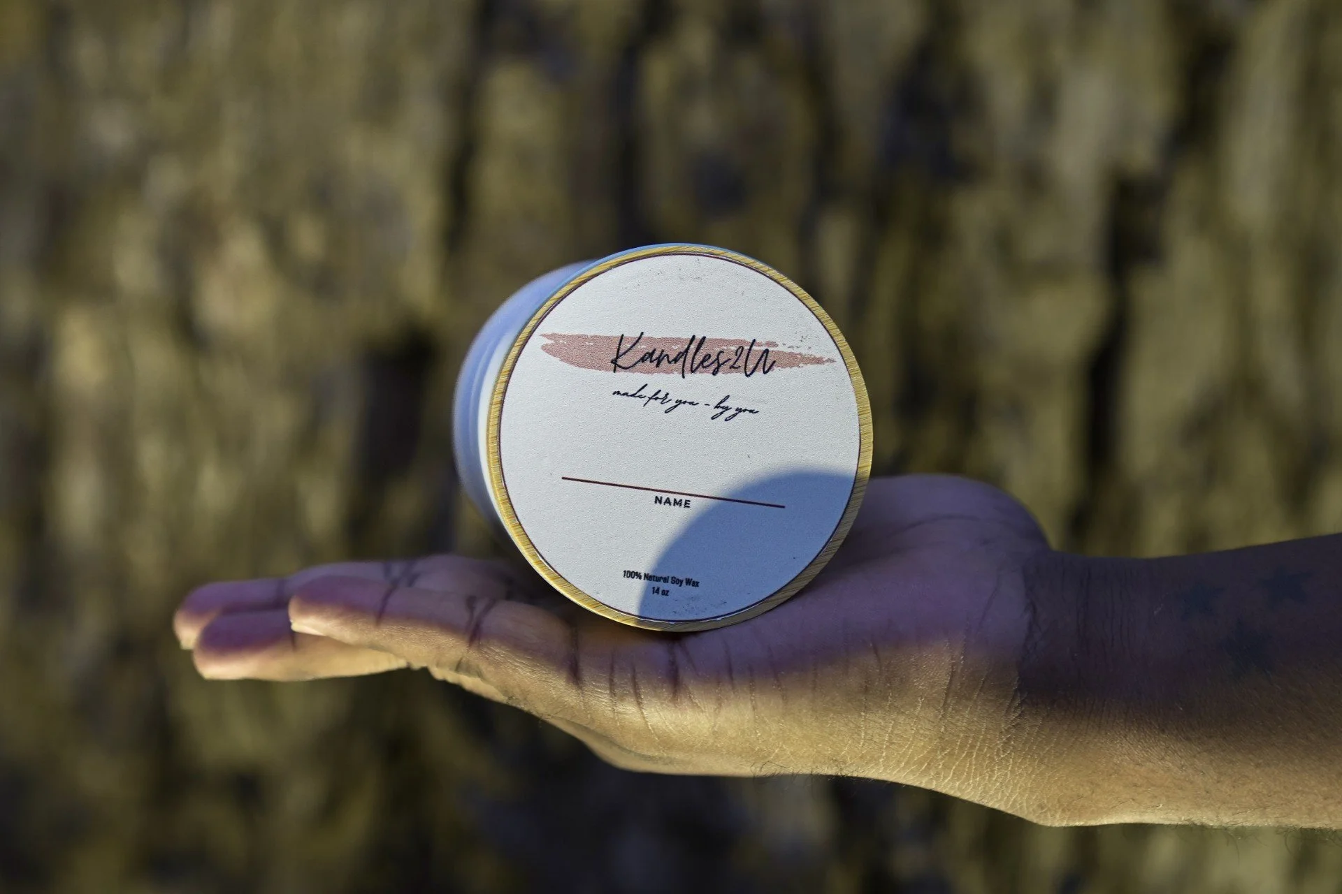 A Kandles2u Candle outside being held by someone close to a tree in Austin Texas for a Candle Making Class. 