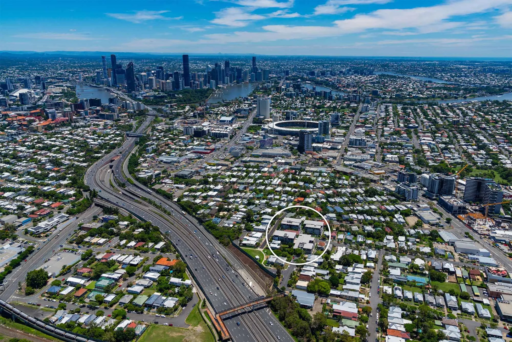 Aerial view of downtown Brisbane, Queensland, Australia, with skyscrapers, bridges over the Brisbane River, and a busy highway.