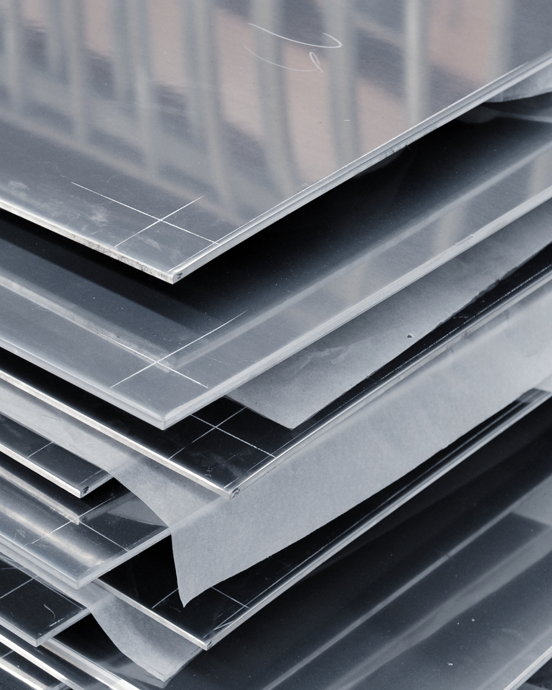Stacked sheets of metallic and coated metal materials.