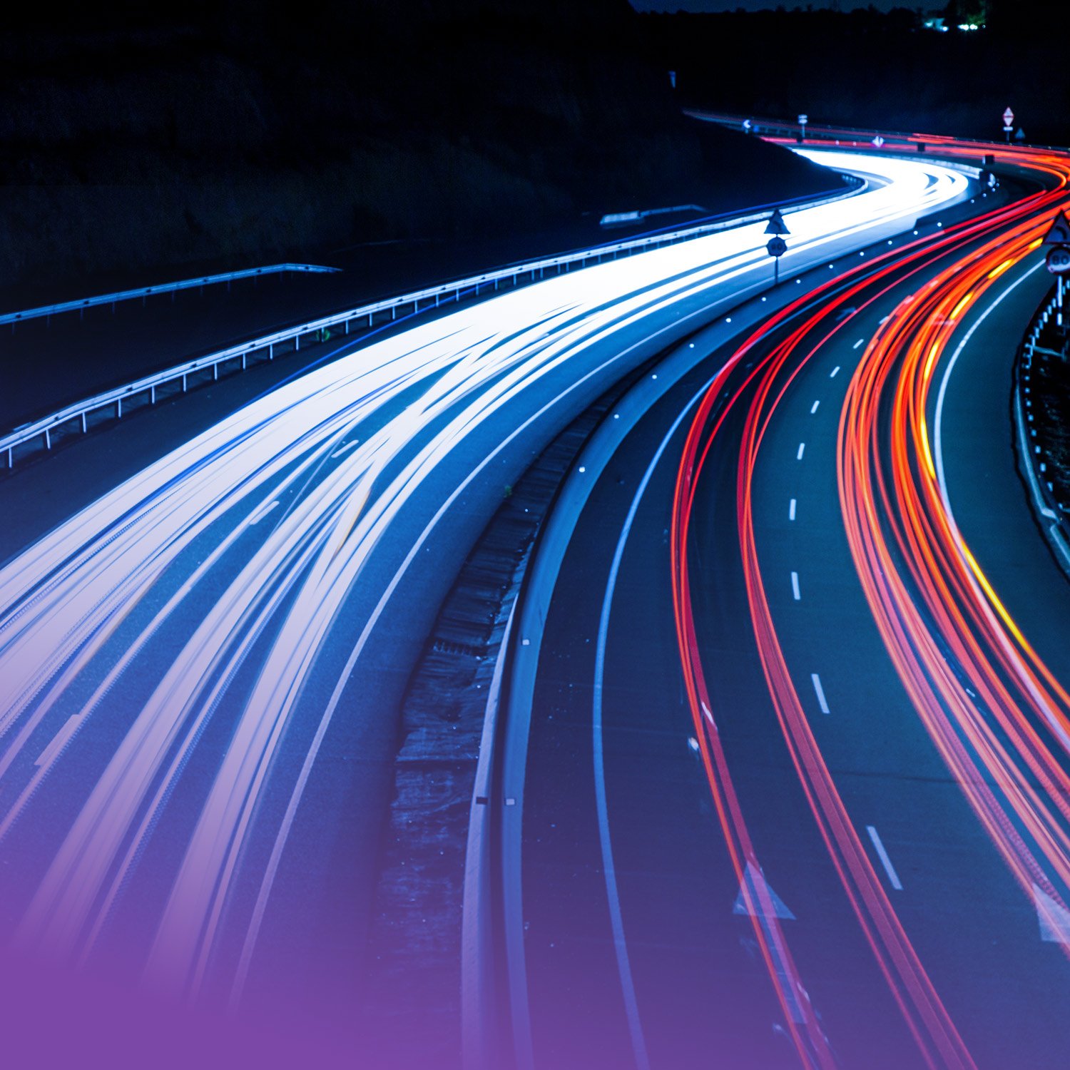 Nighttime view of a highway with streaks of white and red light trails from moving vehicles, showing multiple lanes and curves