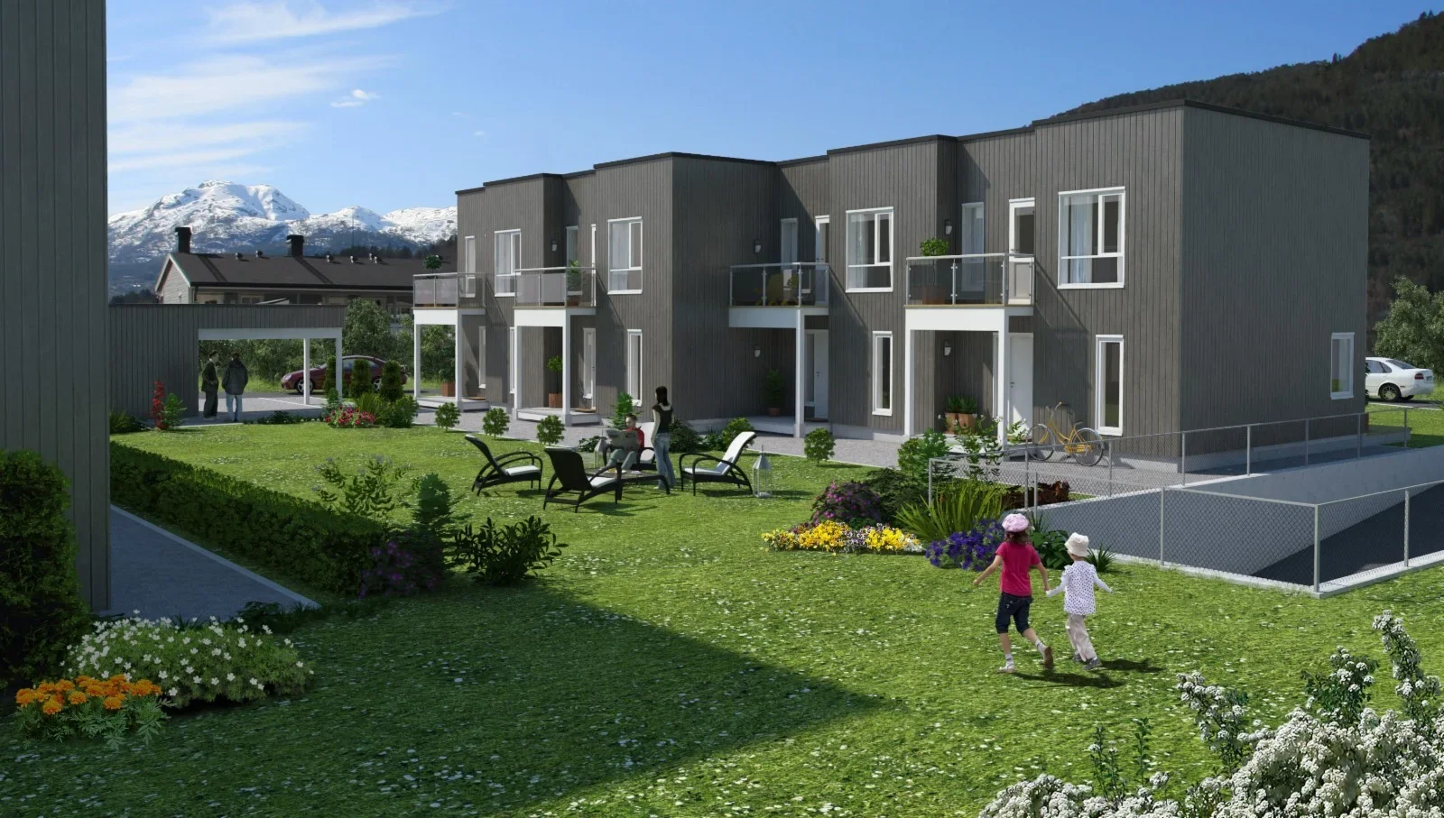 Nærbilde av et nybygd leilighetskompleks med flere leiligheter, omgitt av en velstelt hage med barn som leker, voksne som slapper av og går, og fjell i bakgrunnen.