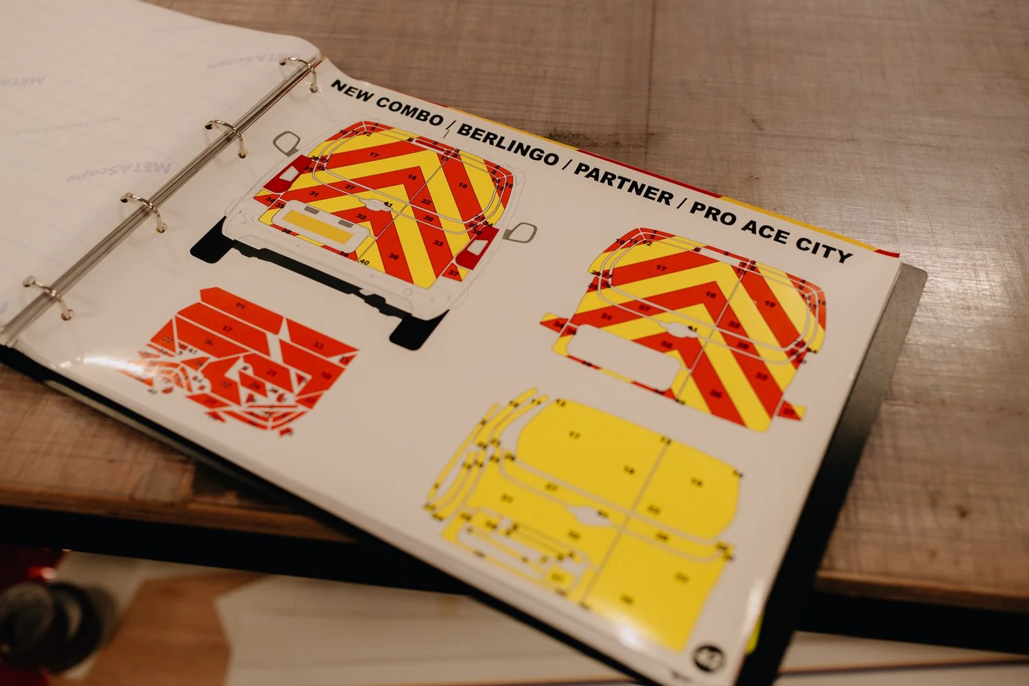 Open photo album showing illustrated plans for a dartboard game setup with color-coded sections and wiring diagrams, labeled with various sponsor names at the top.