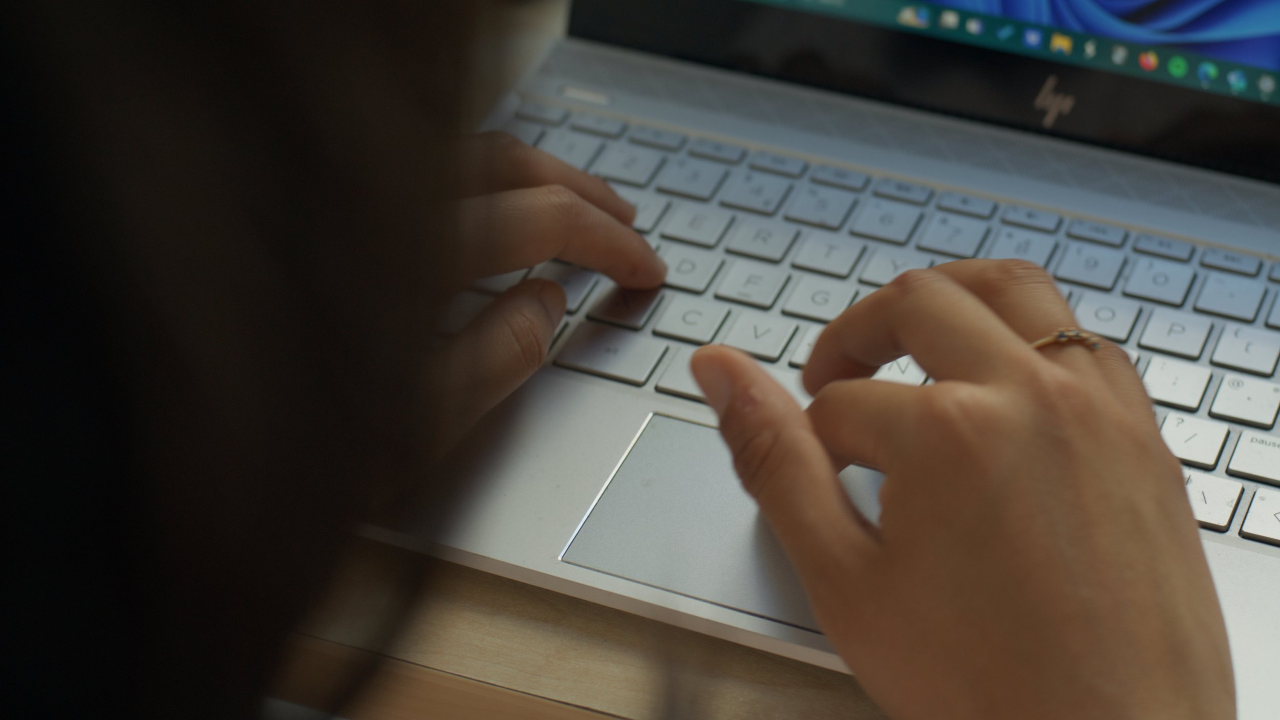 Close-up of a person's hands typing on a white laptop keyboard.