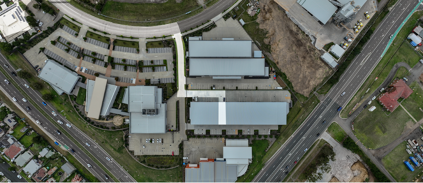 Aerial view of a commercial or institutional complex with multiple buildings, parking lots, and surrounding roads.