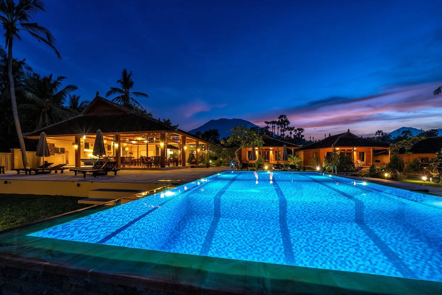 Bali aften billede resortet set fra havet af, med pool med violet himmel og bjerge i baggrunden