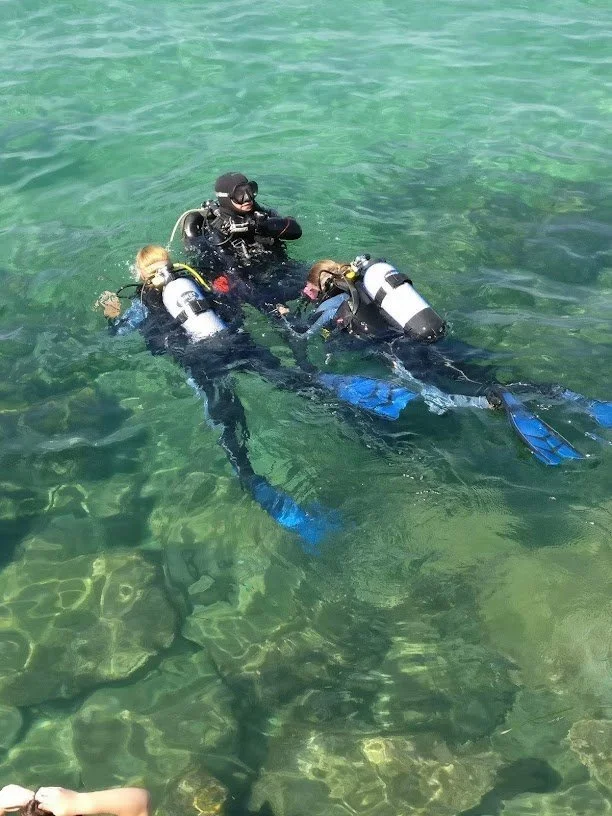 to dykkere svømmer i overfladen med deres instruktør på Gozo (Malta)