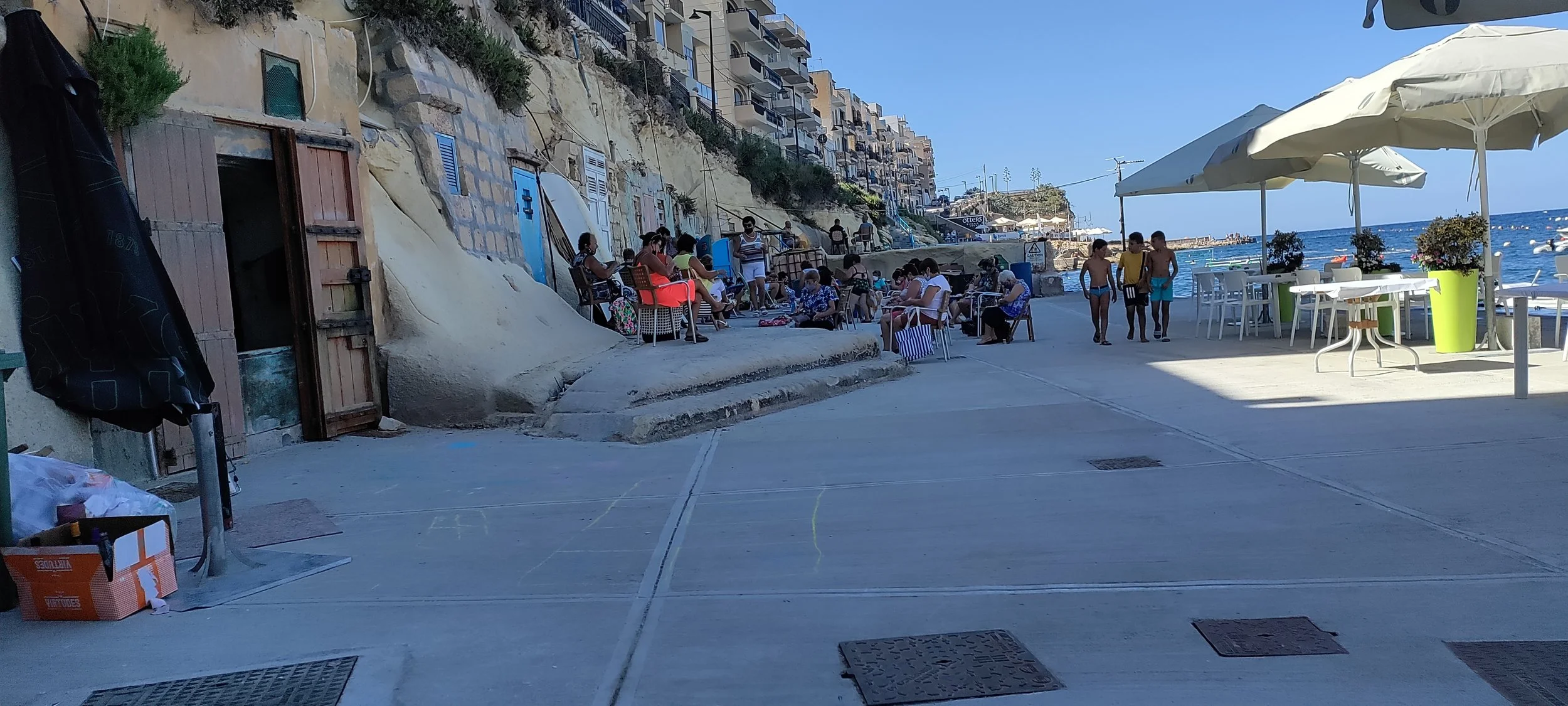 Hyggeligt havneliv på Gozo med banko ved vandet og drenge i badebukser