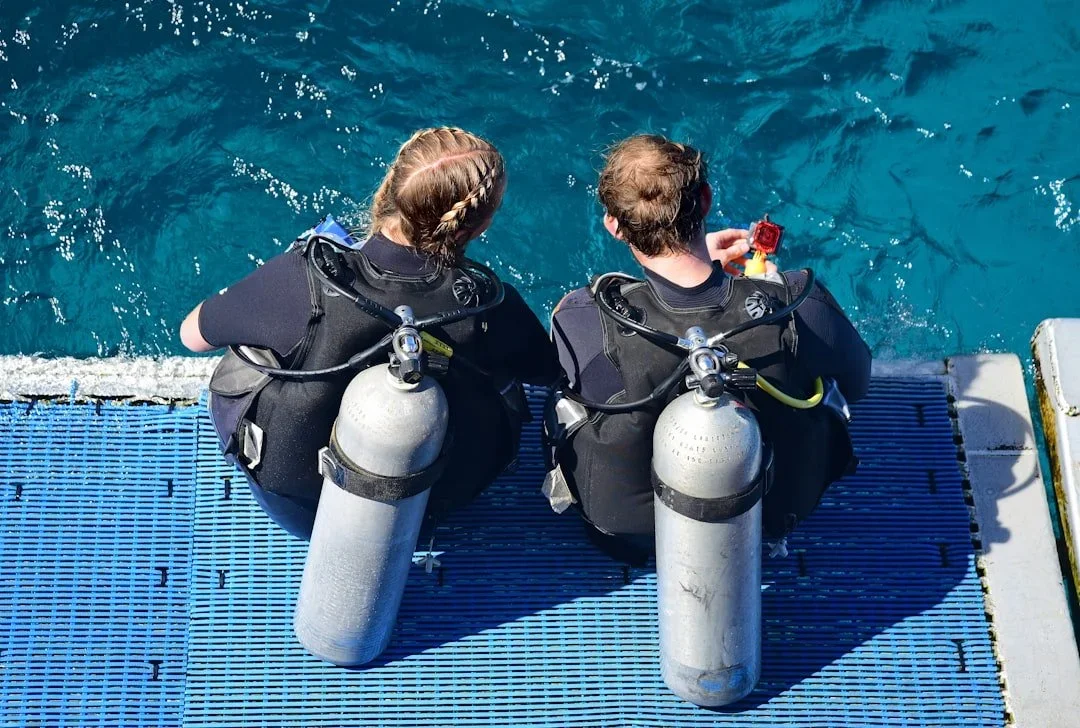 To dykkere sidder på molen efter et dyk på Gozo
