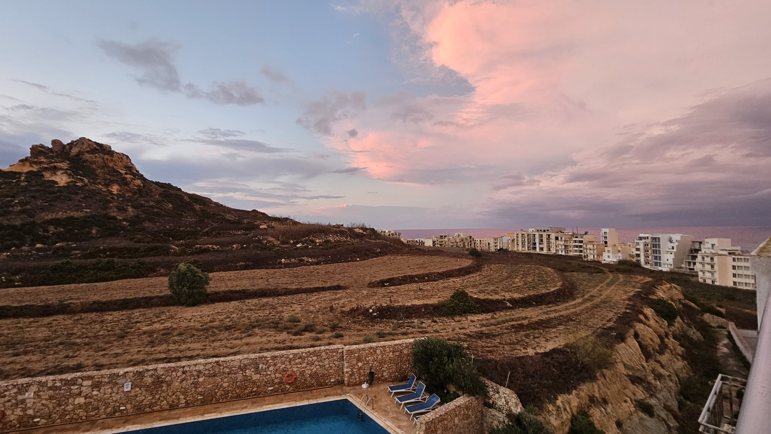solnedgang med udsigt til gozo bjergtop havet og pool ved Marsalforn