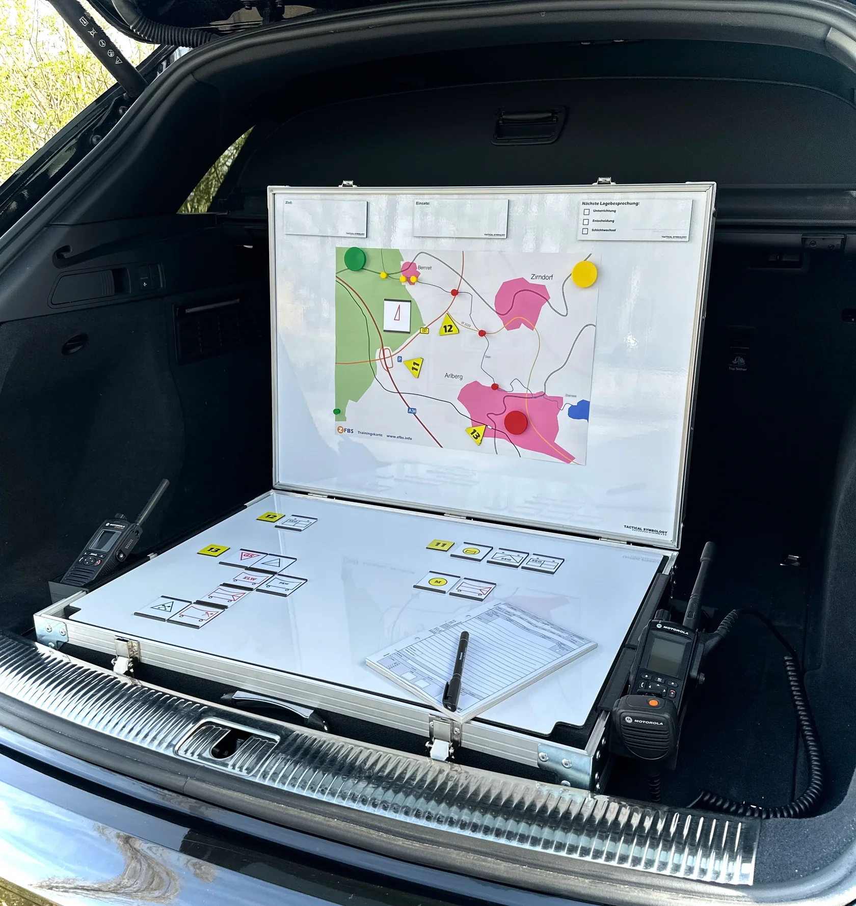 Map e strumenti di comunicazione e pianificazione in una macchina, con mappe, schede e radio comunicatore.