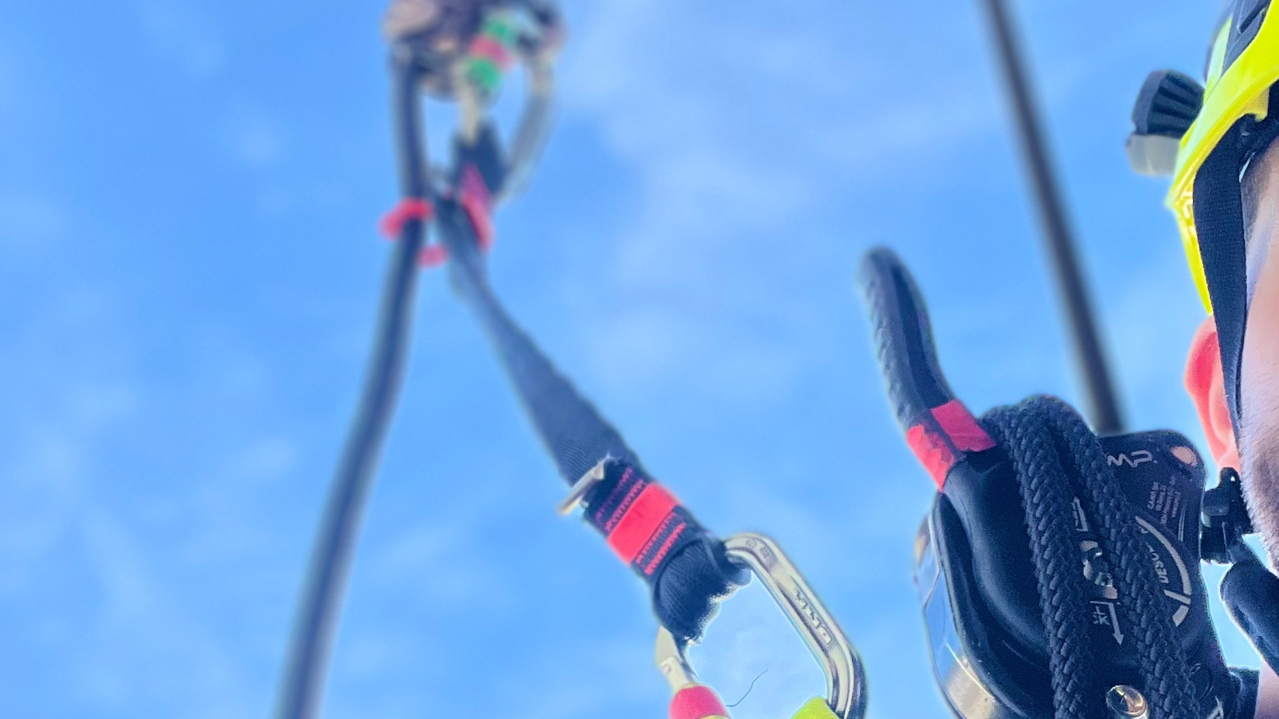 Particolare di un impianto di parapendio vista dal basso, con le funi e le parti di sicurezza visibili contro il cielo.