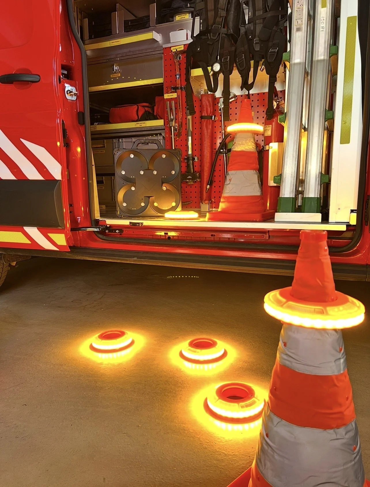 Interno di un veicolo dei vigili del fuoco con strumenti e attrezzature, incluso un operto stradale di segnalazione con luci lampeggianti.