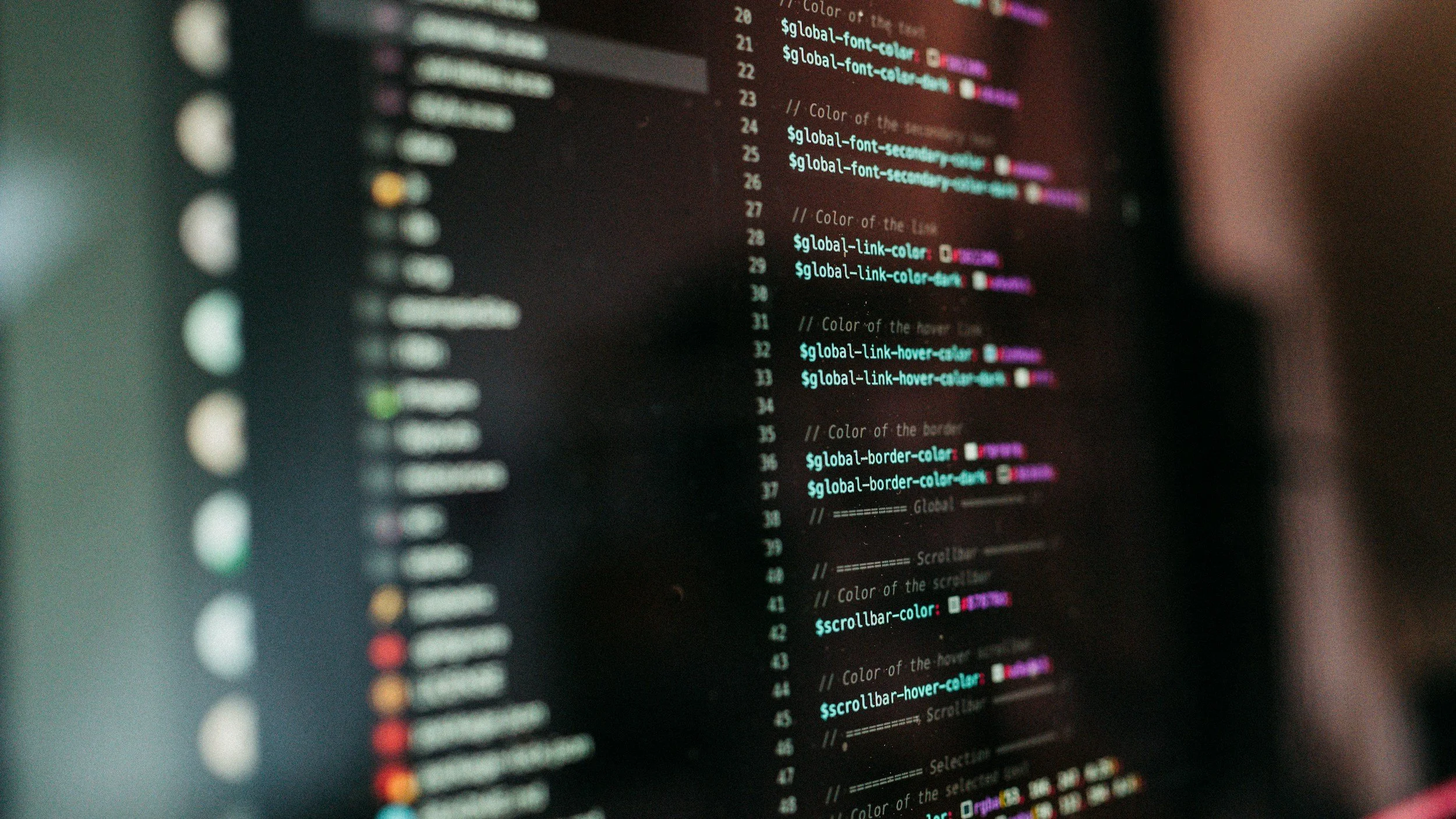 Close-up of a computer screen displaying colorful code or script, with lines highlighted in different colors such as pink, blue, purple, and red.