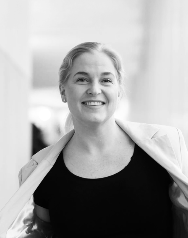 Laura Sulkava henkilökuva, päällä vaalea bleiseri ja musta paita, hymyilee.