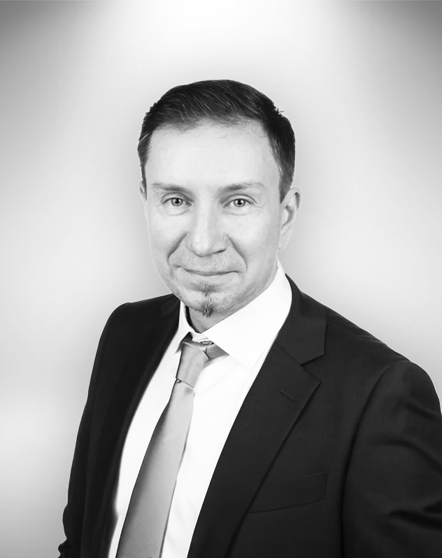 Petteri Redsven henkilökuva, pukeutunut tummaan pukuun päällään vaalea solmio, hymyilee.