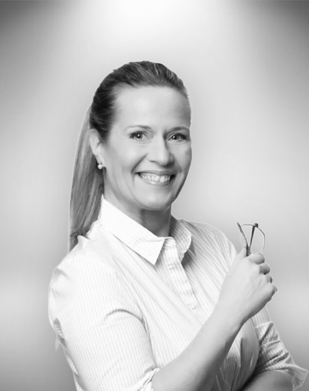 Maria Von Flittner henkilökuva, pukeutunut valkoiseen kauluspaitaan, pitelee kädessään silmälaseja ja hymyilee leveästi.