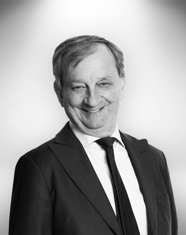Hjallis Harkimo henkilökuva, pukeutunut puvuntakkiin ja kravattiin, hymyilee.