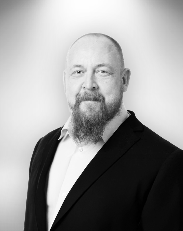 Jari Smedberg henkilökuva, pukeutunut mustaan pukuun, kaulus hieman auki, hymyilee.