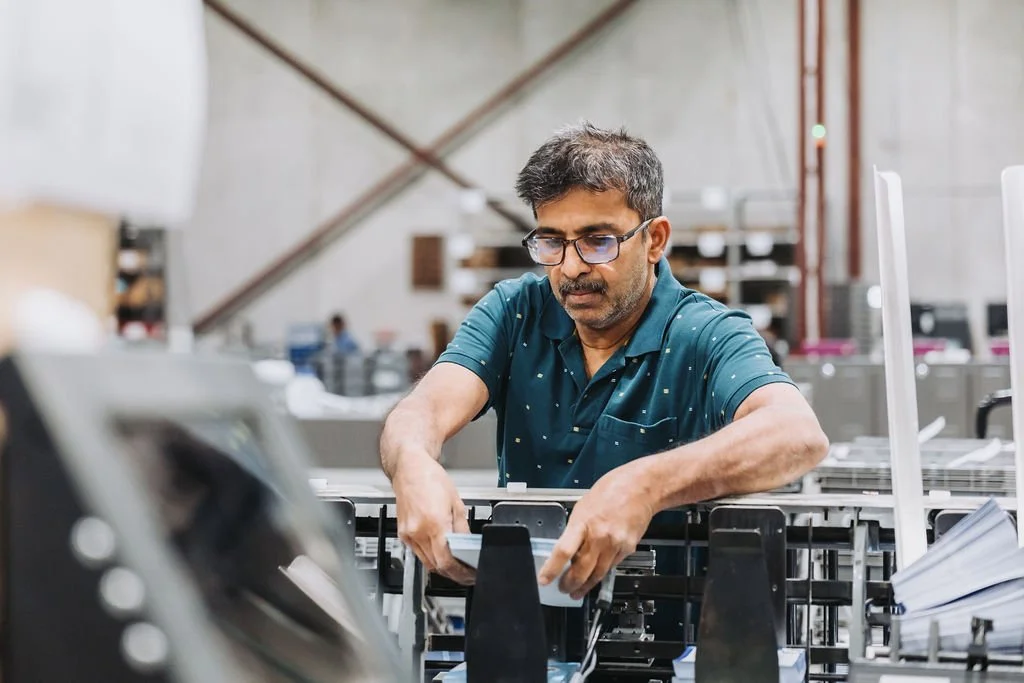 Male production operator working with printing and mailing equipment at Marketing Kitchen.