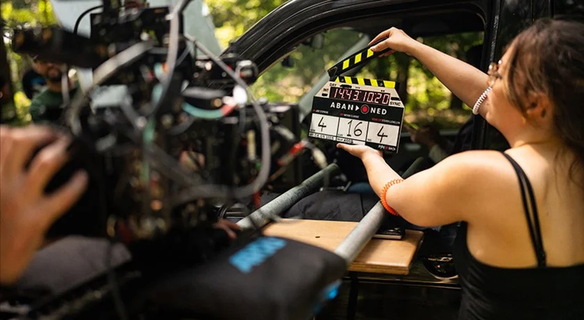 Behind-the-scenes image of the clapperboard on location in the forest during production of the hybrid found footage horror film Abandoned.