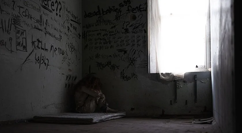 ⁠Sadie cries alone in a prison cell in this eerie production still from Abandoned, a found footage horror film exploring psychological distress.