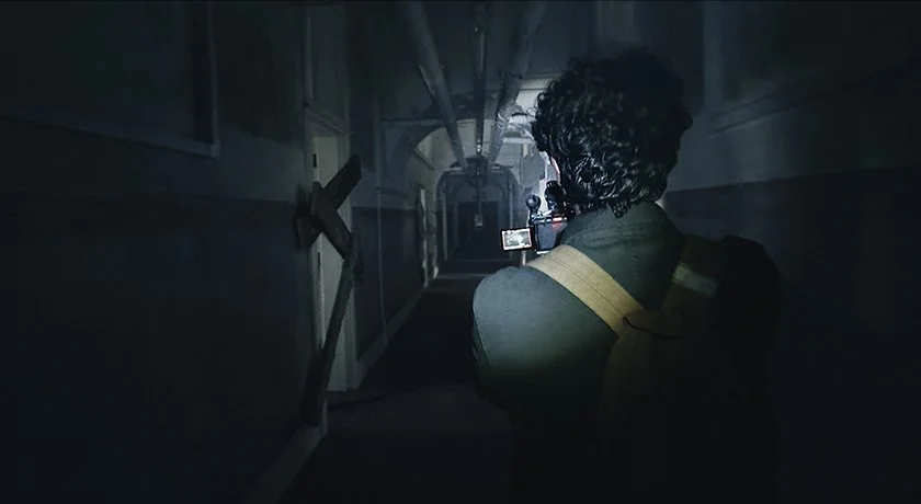 Atmospheric production still from the found footage horror movie Abandoned, showing character Adam exploring a dark hallway as mystery and suspense unfold.