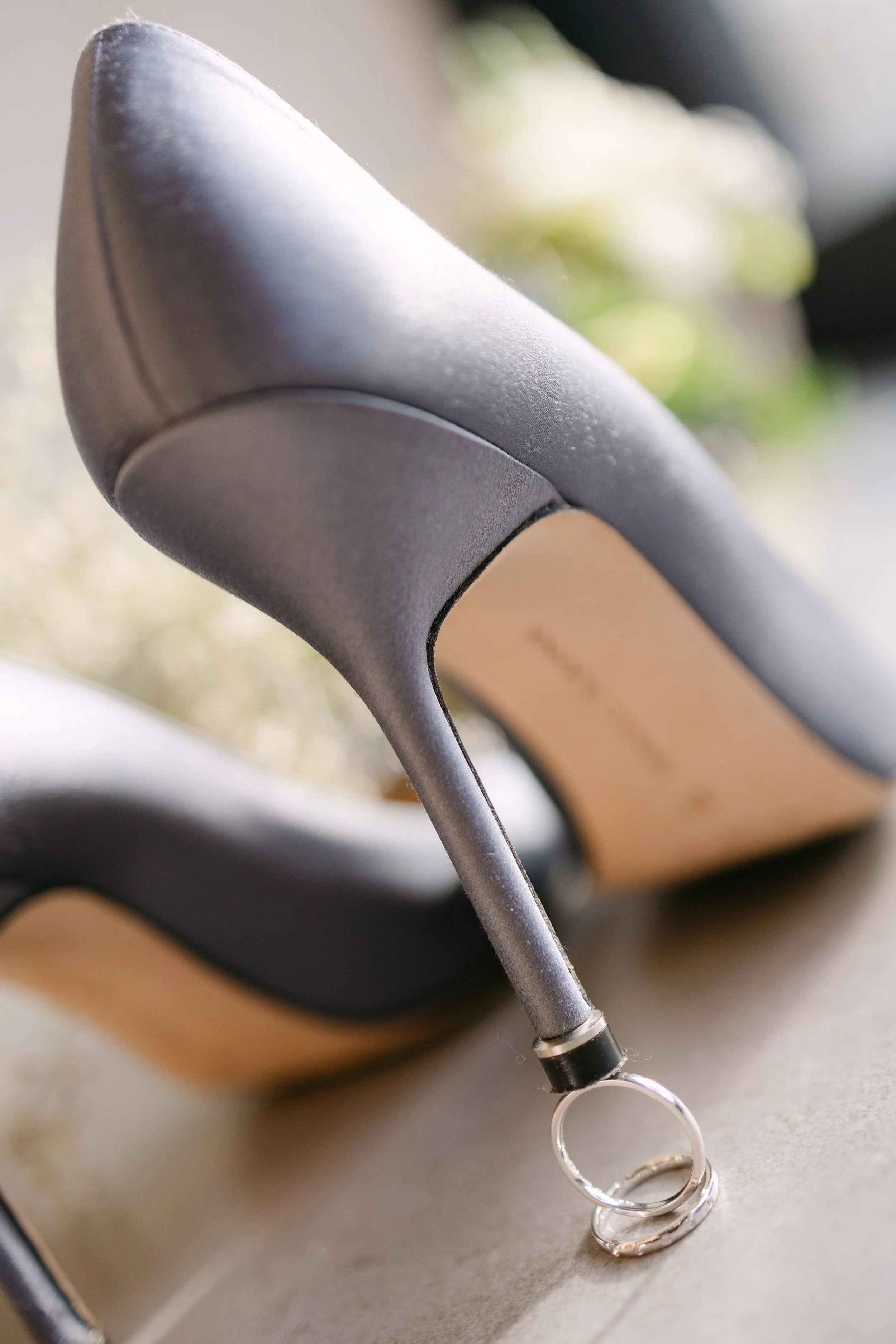 Close-up of a black high-heeled shoe with a decorative ring attached to the heel.
