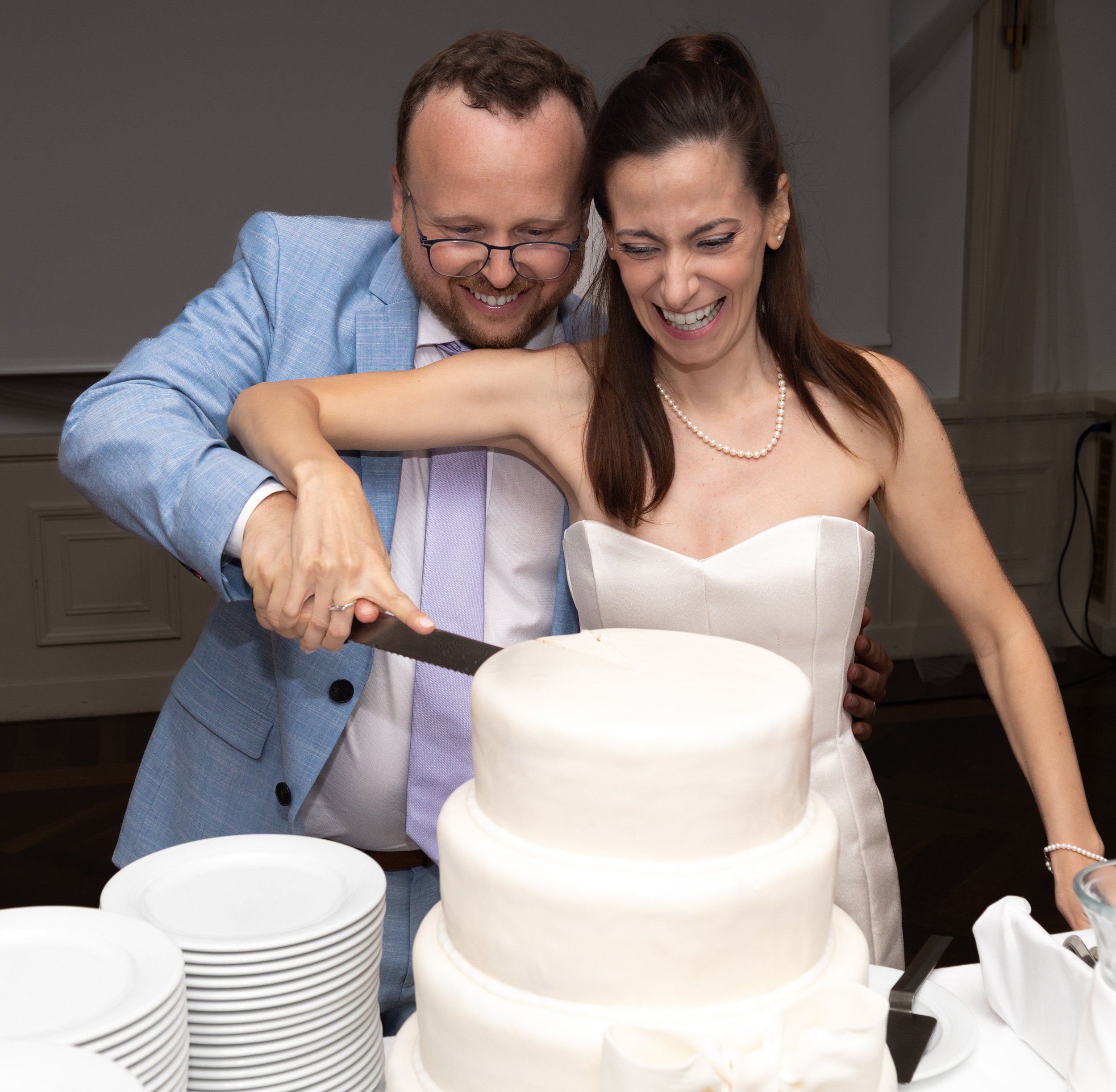 A bride and groom cutting a wedding cake together at their wedding reception.