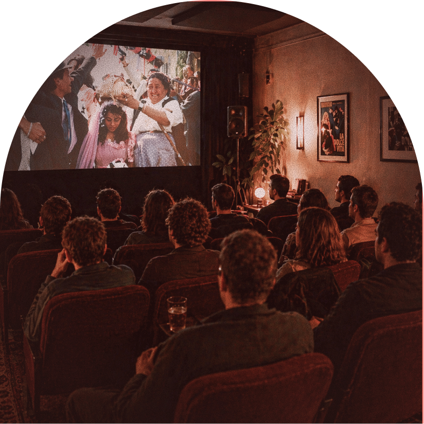 People watching a movie in a cozy theater with vintage decor and framed posters on the wall.