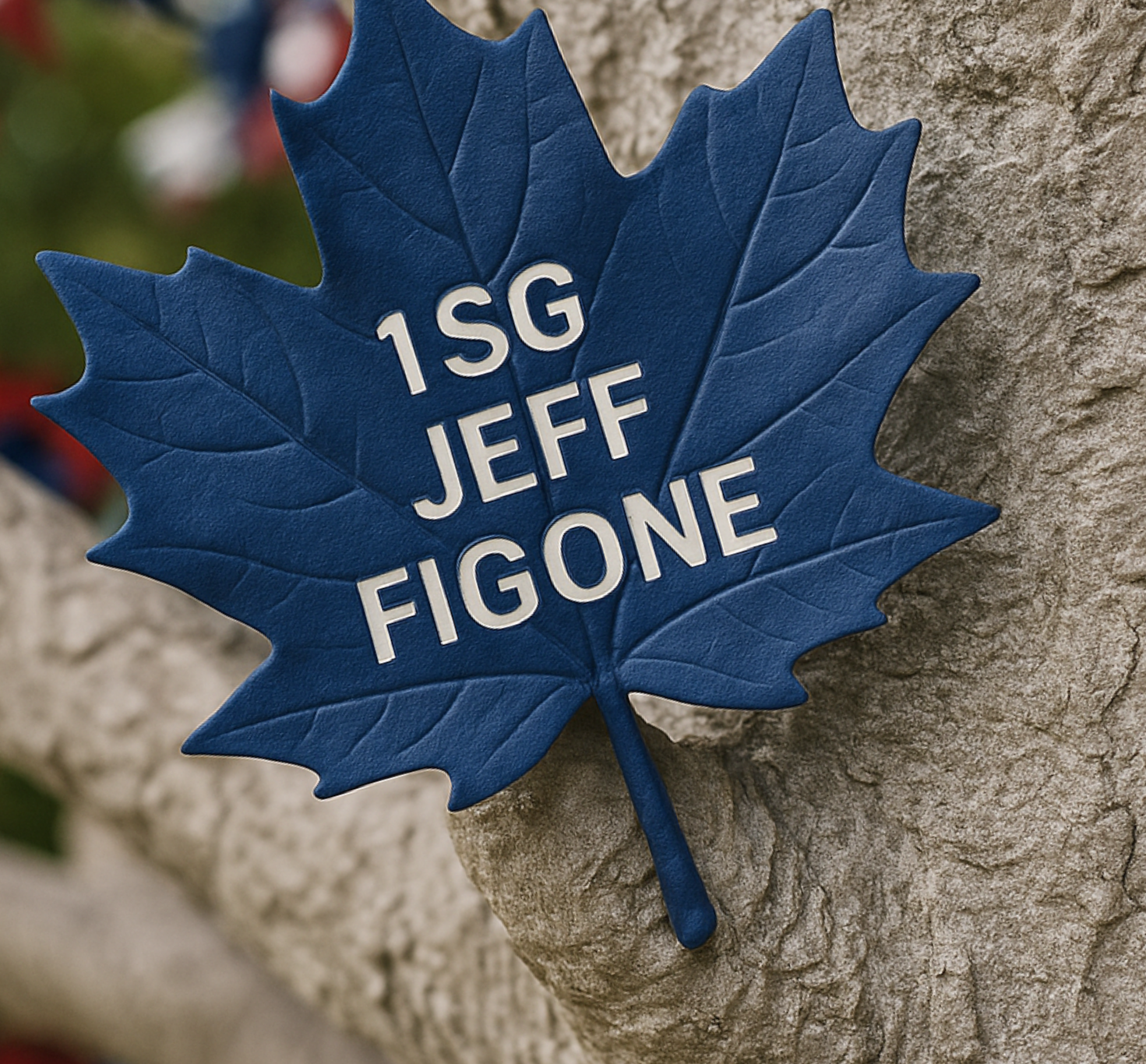 A blue maple leaf pin with white text that reads '1SG JEFF FIGONE', attached to a textured gray stone surface.