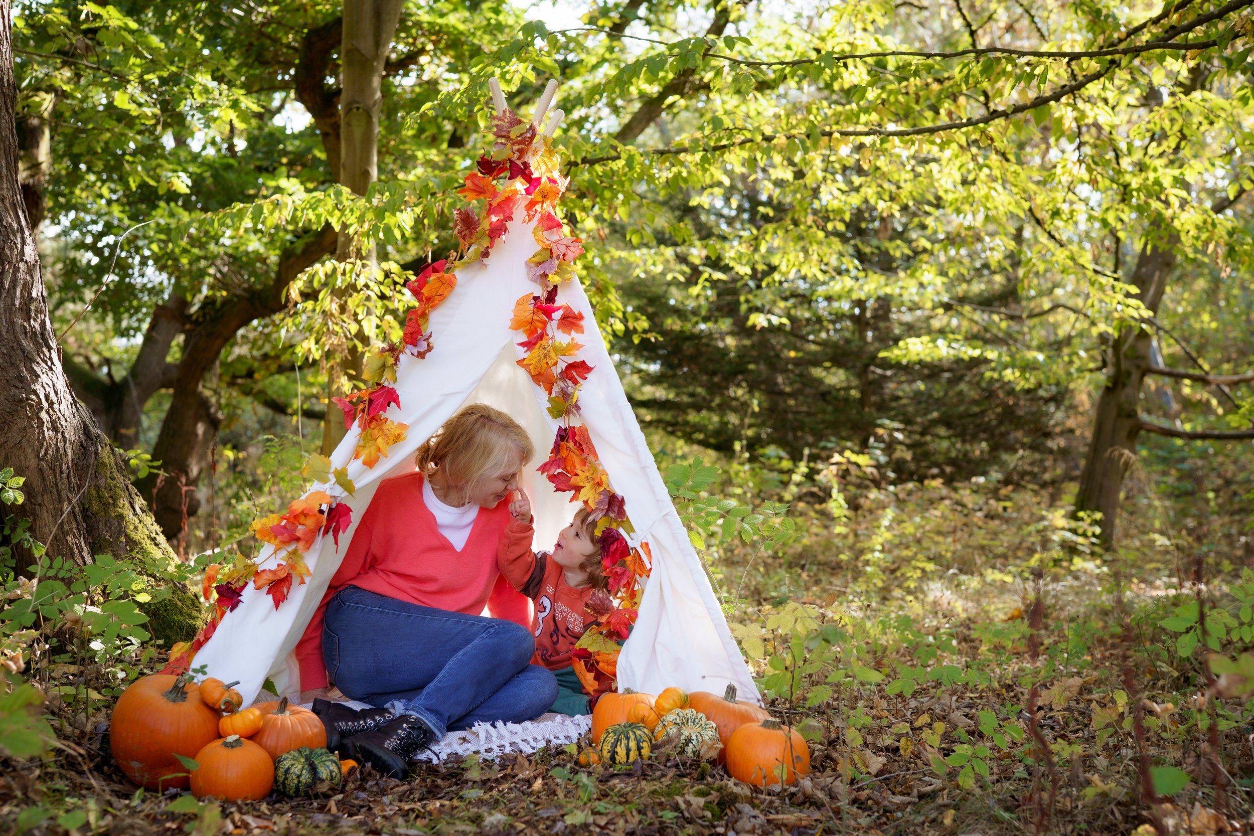 A family sitting on a blanket on the grass laughing and playing with a young girl in the Buckinghamshire countryside
