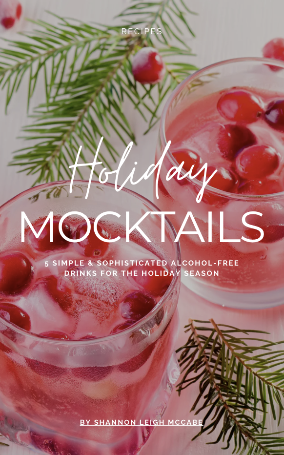 Festive mocktails with cranberries and ice in glasses, surrounded by pine sprigs. Text overlay: "Holiday Mocktails" by Shannon Leigh McCabe.