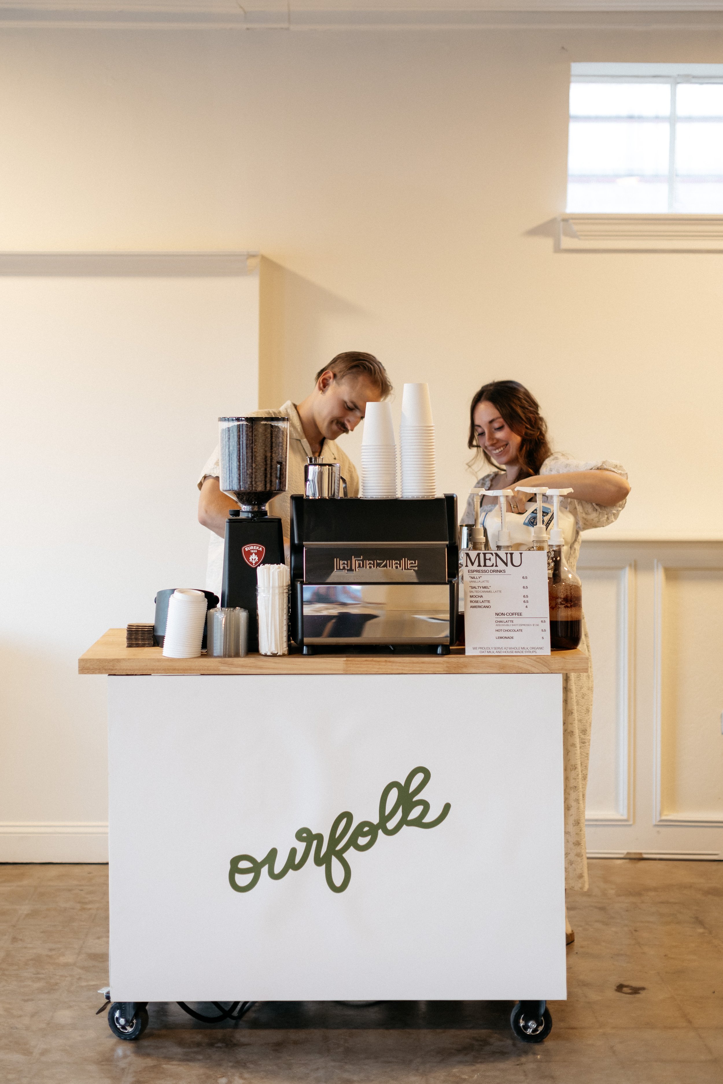 A coffee cart in Wichita Kansas with two friendly baristas smiling while making a drink